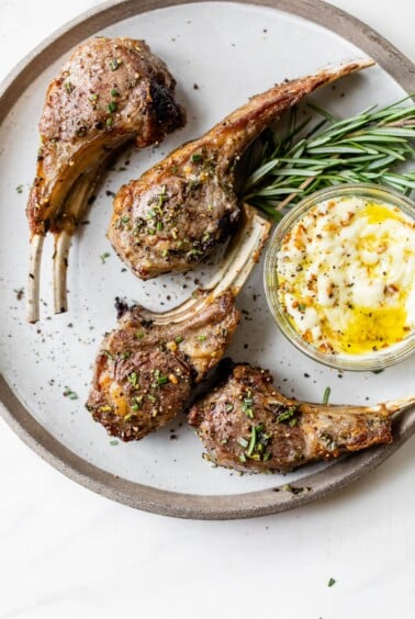 cooked lamb chops on a plate next to a small dish of aioli