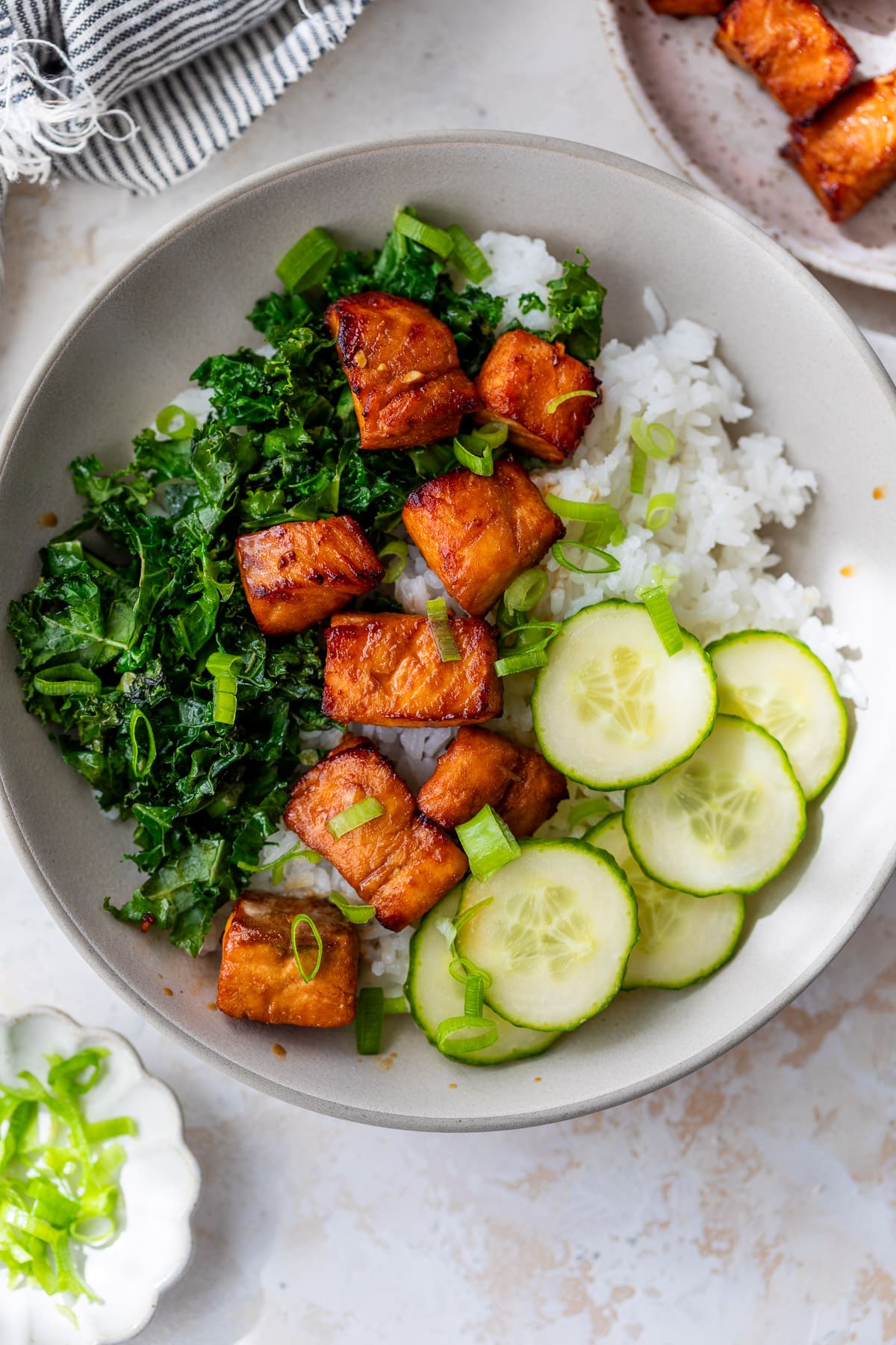 air fryer salmon bites on top of a cucumber, kale, and rice bowl.