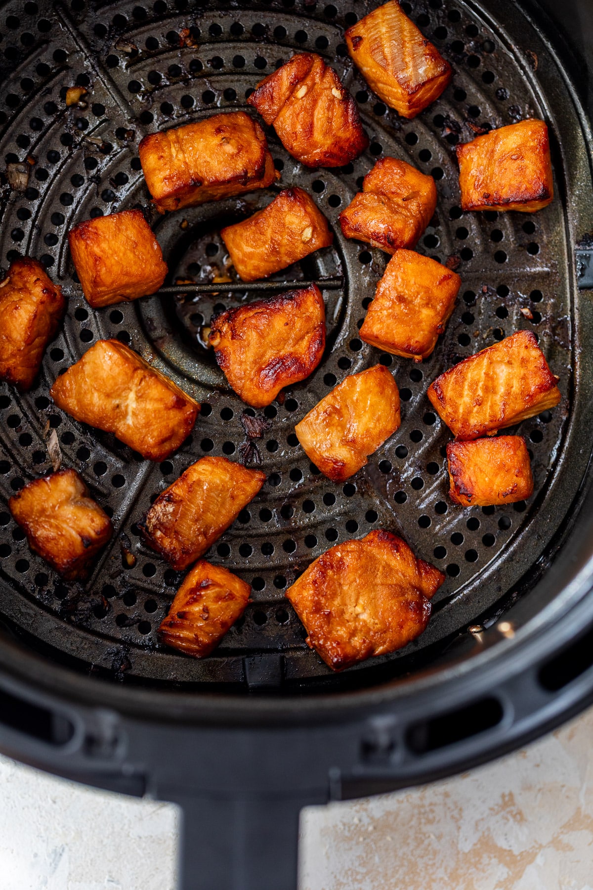 cooked salmon bites in an air fryer basket.