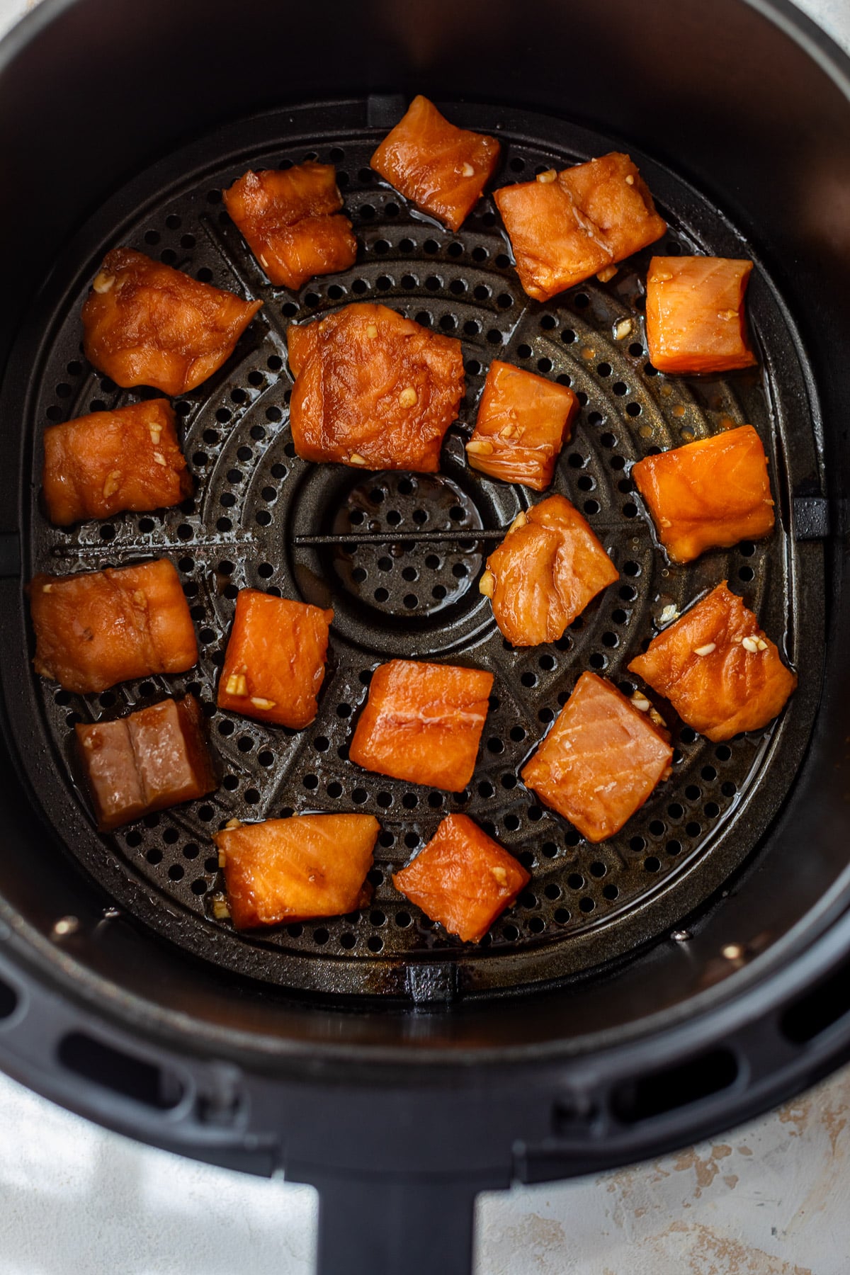 cooking raw salmon bites in an air fryer.