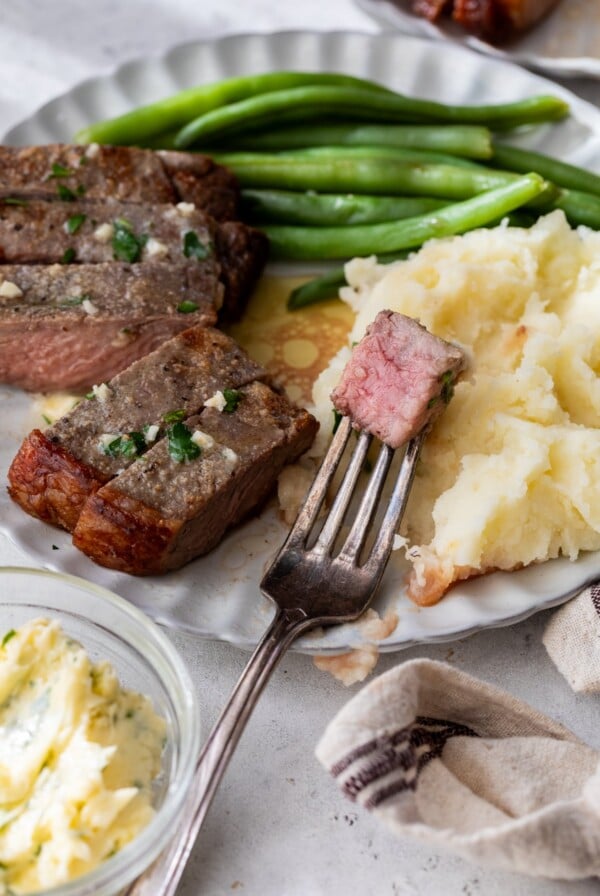 air fryer steak sliced on a plate with green beans and mashed potatoes
