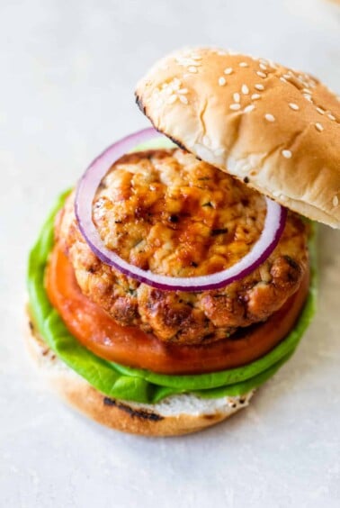 a turkey burger sandwich with a bun, lettuce, tomato, and red onion