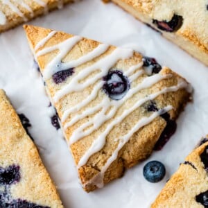 blueberry scones drizzled in a glaze on parchment paper