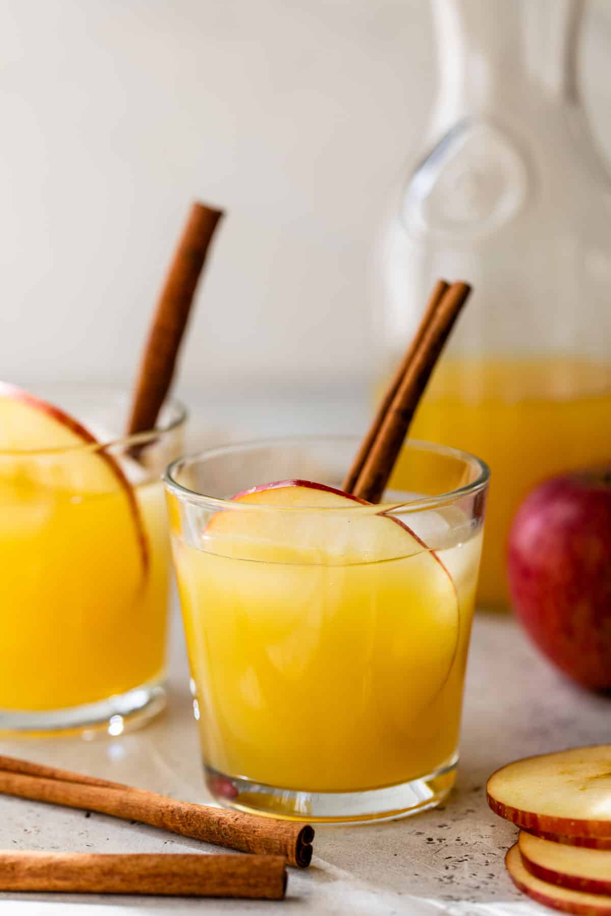 side view of apple cider punch in a glass with ice and a cinnamon stick