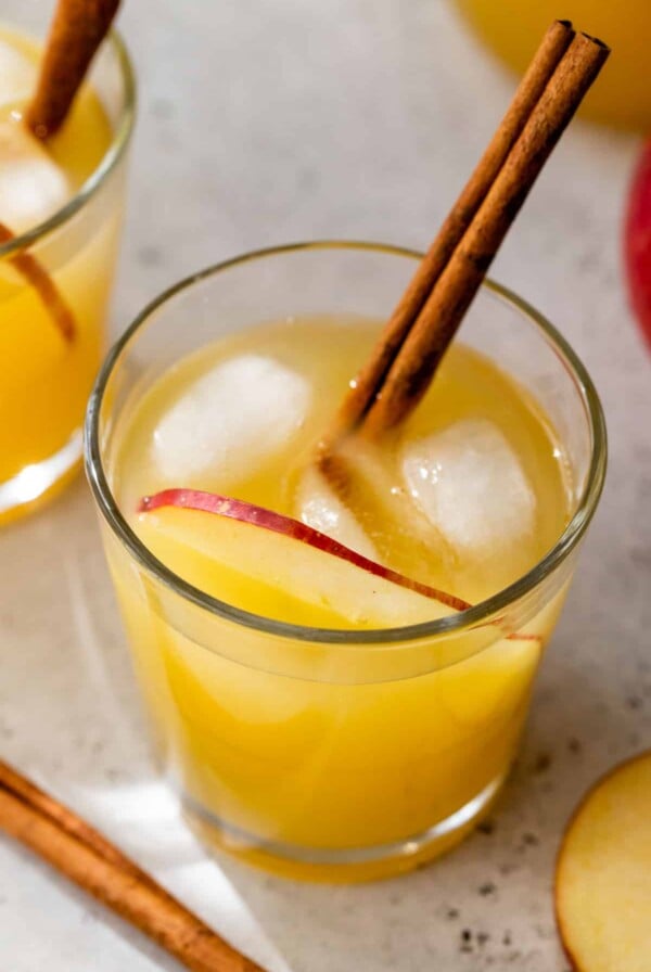 apple cider punch in a glass with ice and a cinnamon stick