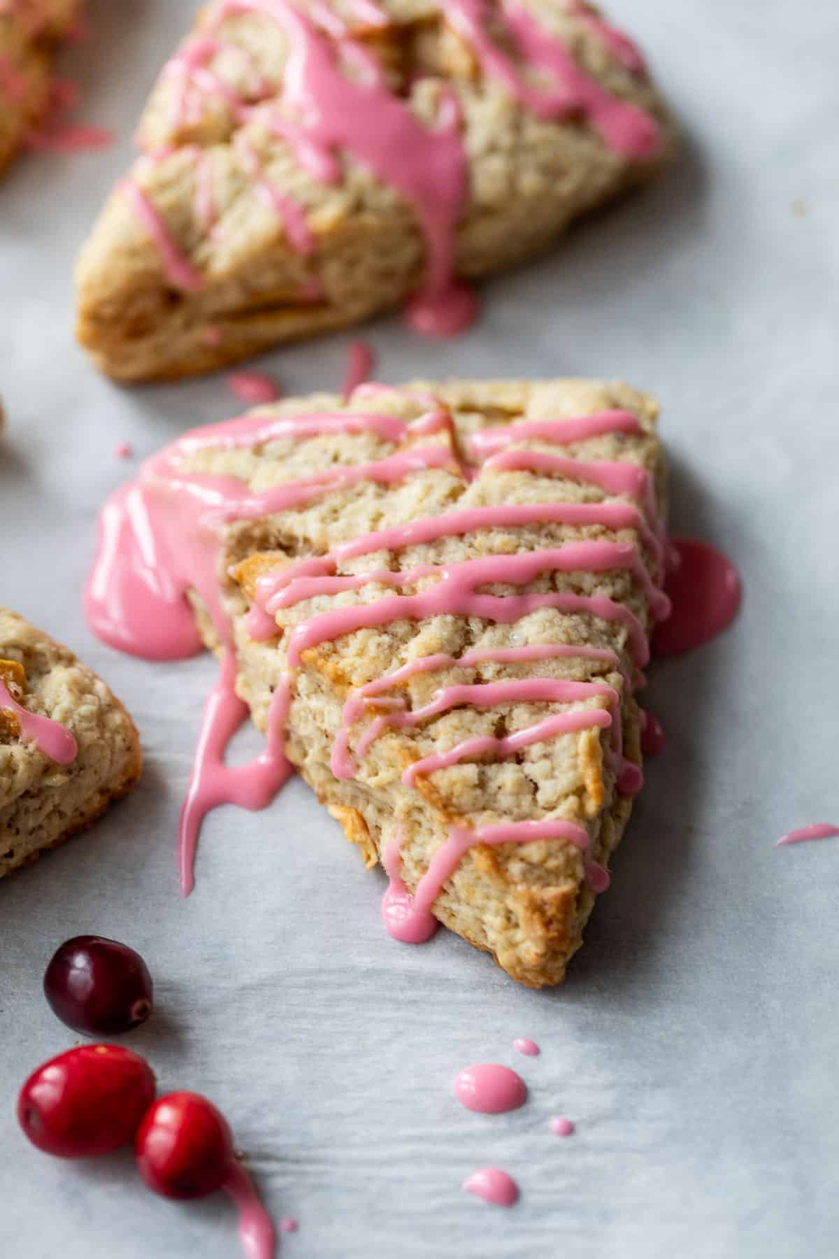 side view of an apple cranberry scone topped with a drizzle of pink cranberry glaze.
