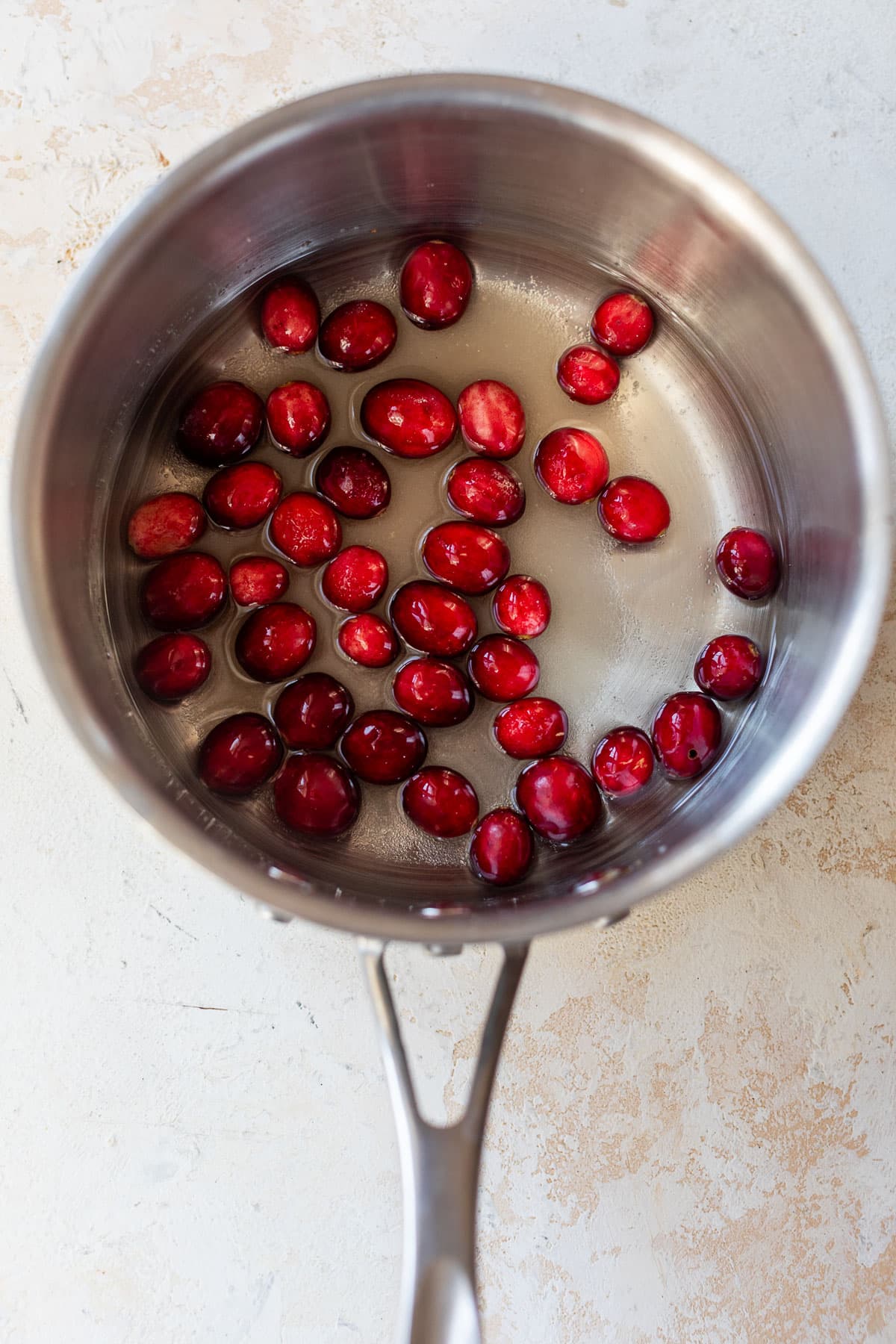 overhead view of the ingredients for cranberry syrup in a saucepan.