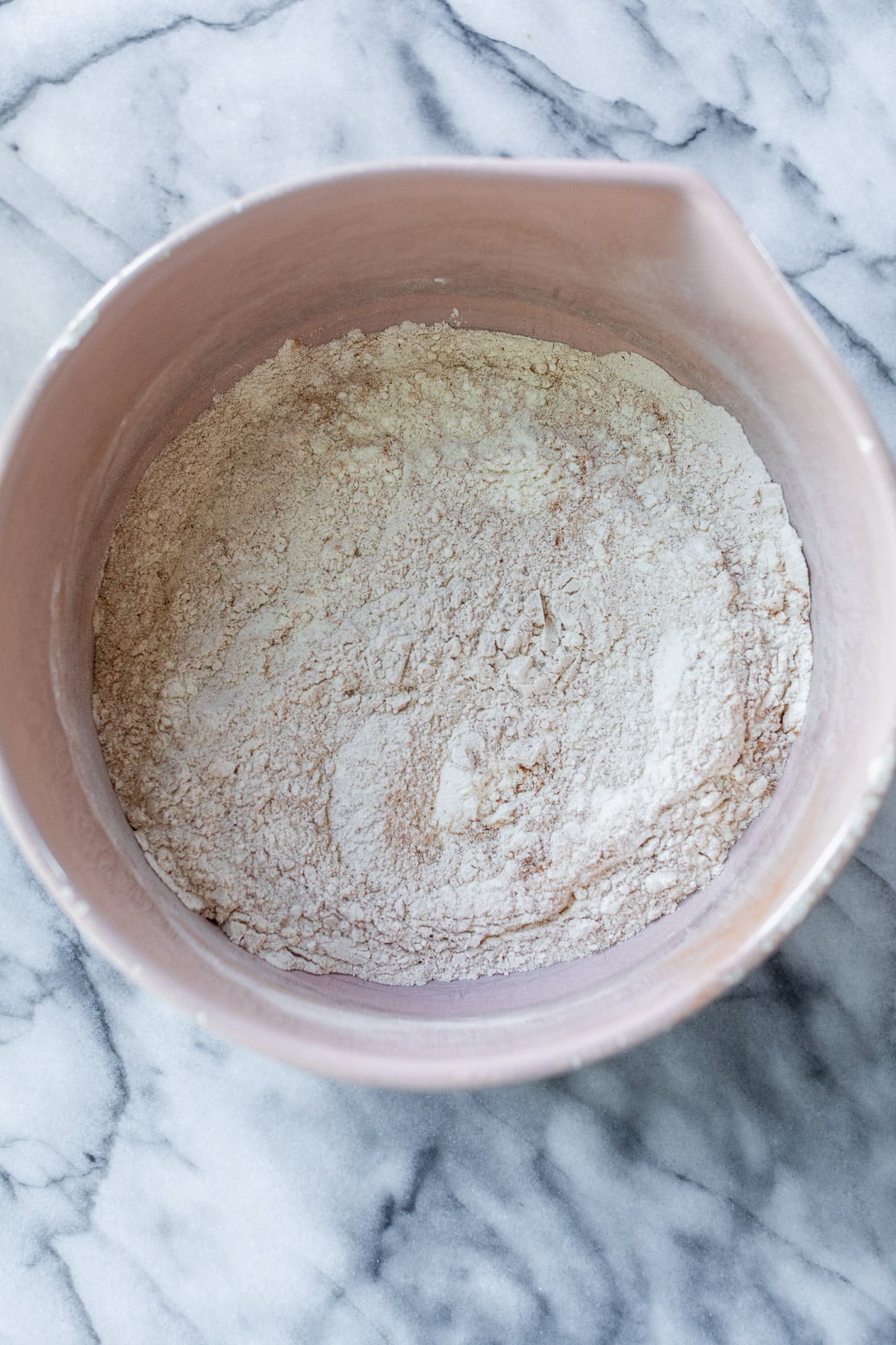 the dry ingredients for apple oatmeal cookies mixed together in a pink bowl.