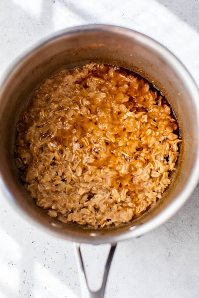 cooked oatmeal in a small saucepan topped with maple syrup