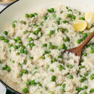 side view of a wooden spoon in a pot of baked risotto.