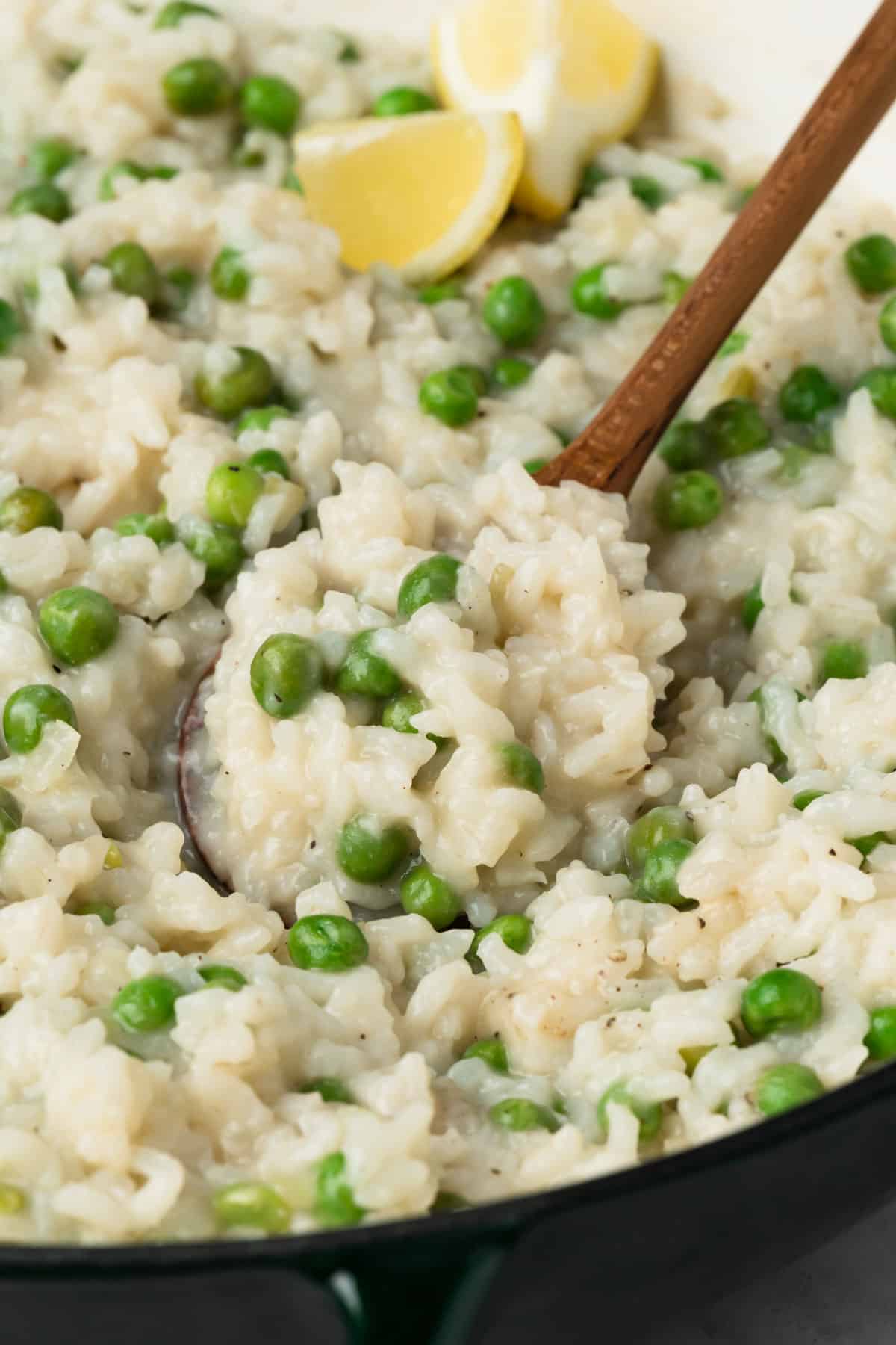 close up on a wooden spoon in a pot of baked risotto.