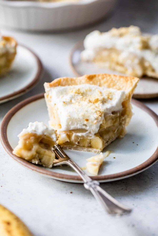 slice of banana pudding pie on a plate with a fork and a bite taken out