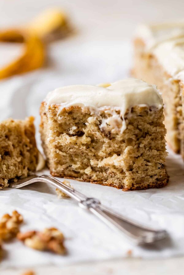 side view of a piece of banana walnut cake with icing and a fork