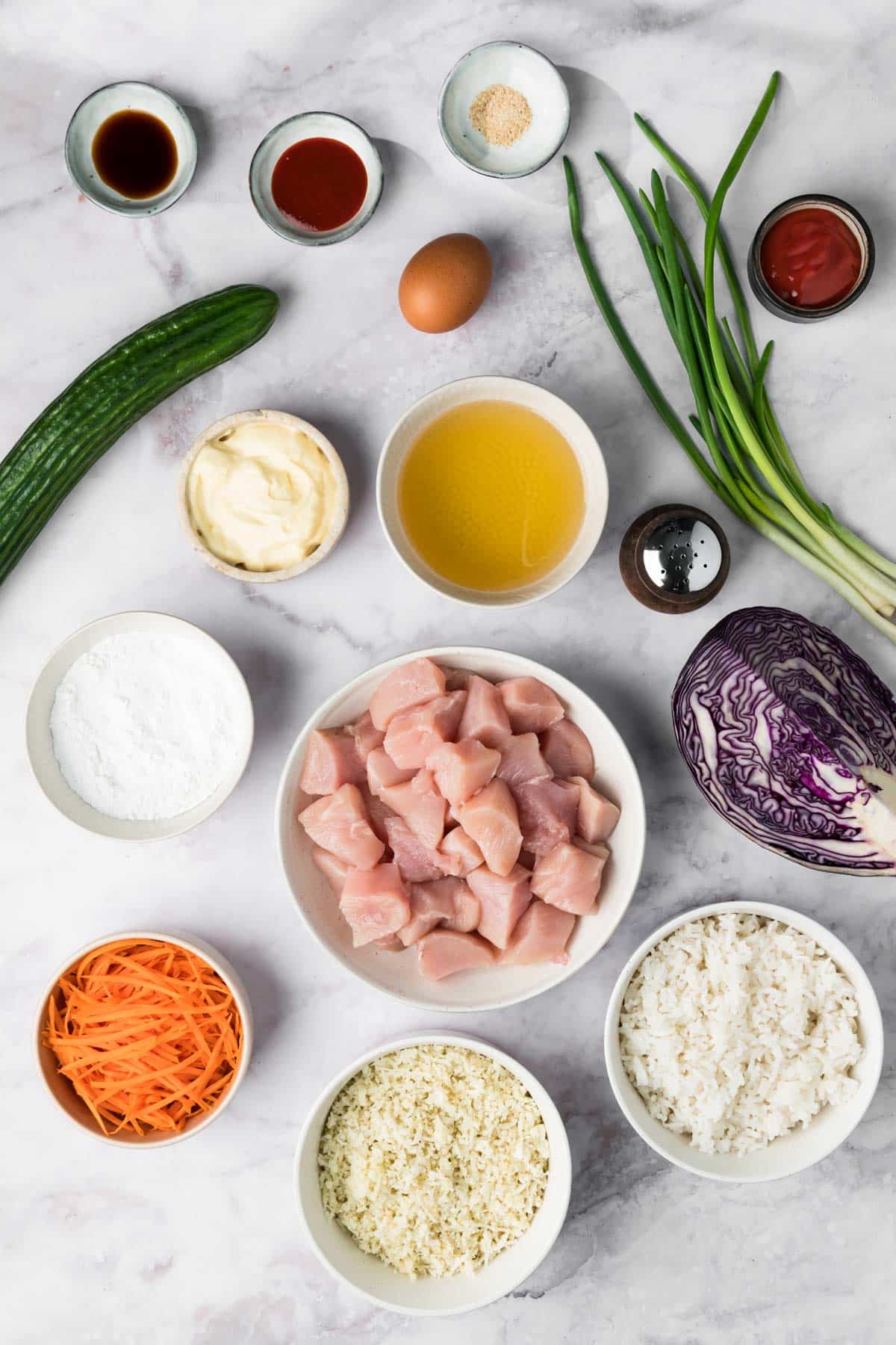 overhead view of the ingredients for bang bang chicken bowls in individual small bowls.