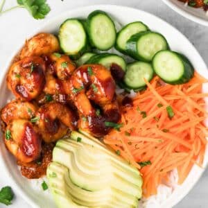 overhead view of a BBQ Shrimp Bowl topped with shrimp, cucumbers, carrots, and avocado.