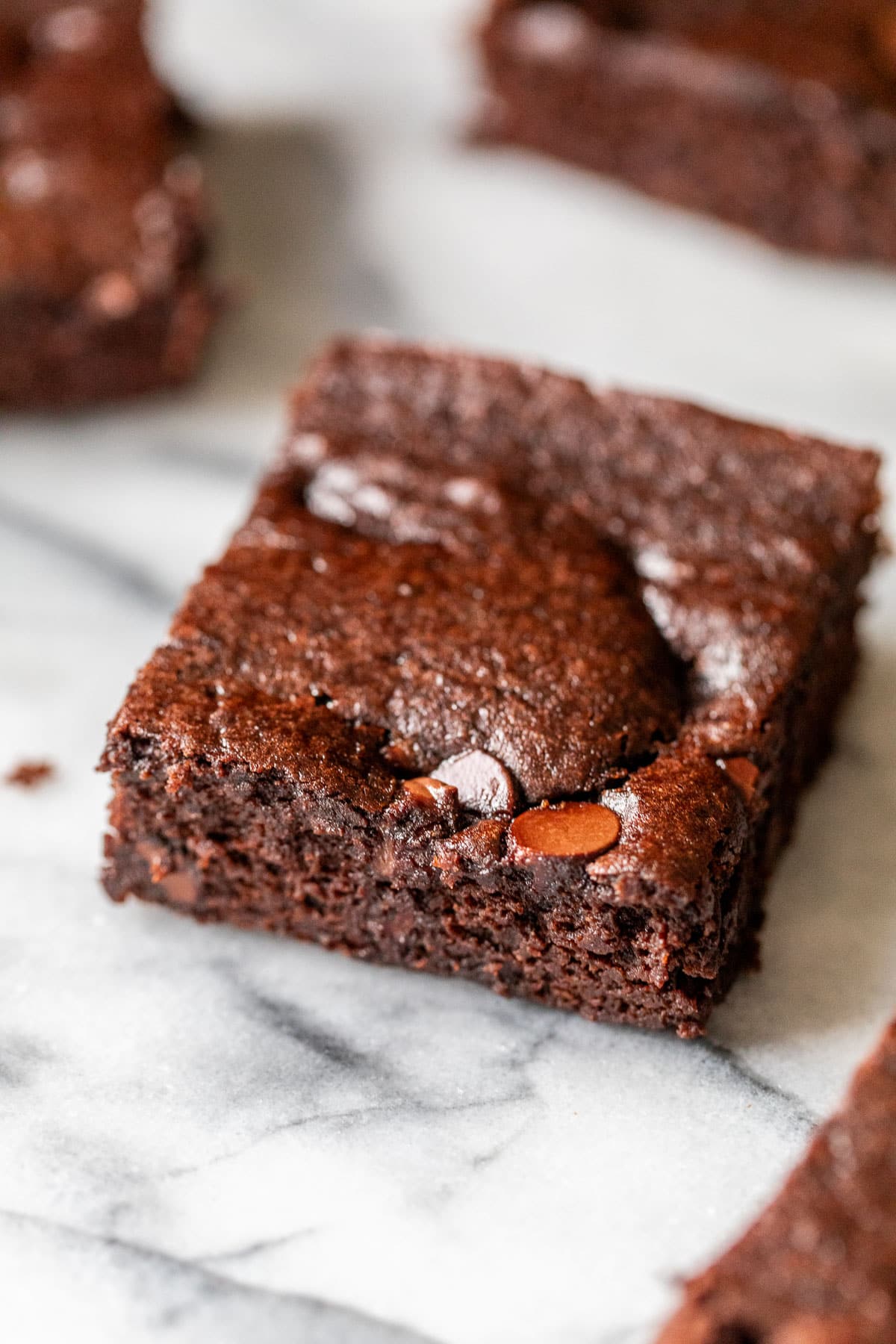close up on a black bean brownie with 2 more brownies in the background.
