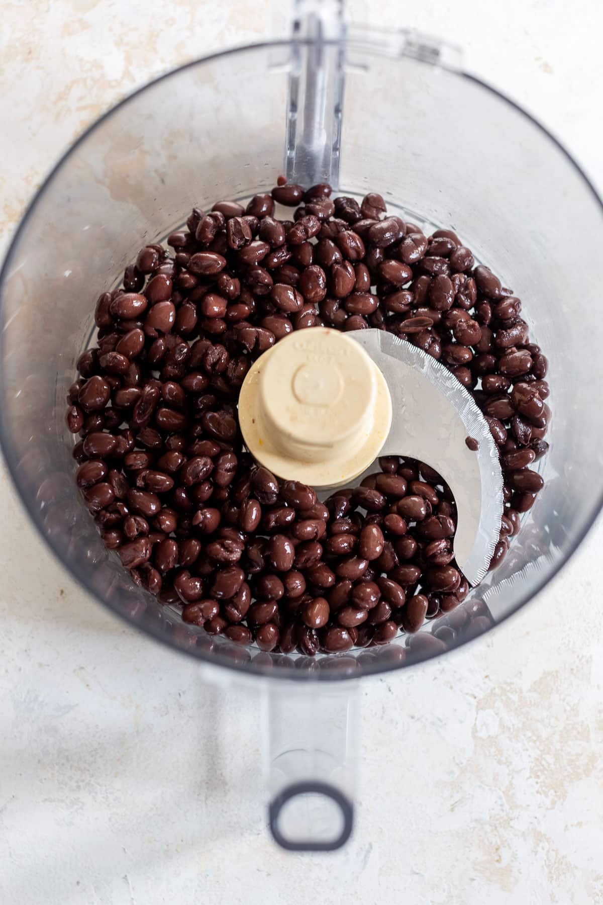 overhead view of black beans in a food processor.