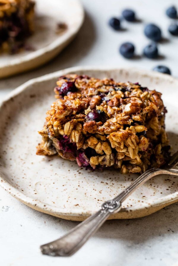 side view of a piece of blueberry baked oatmeal on a plate with a fork