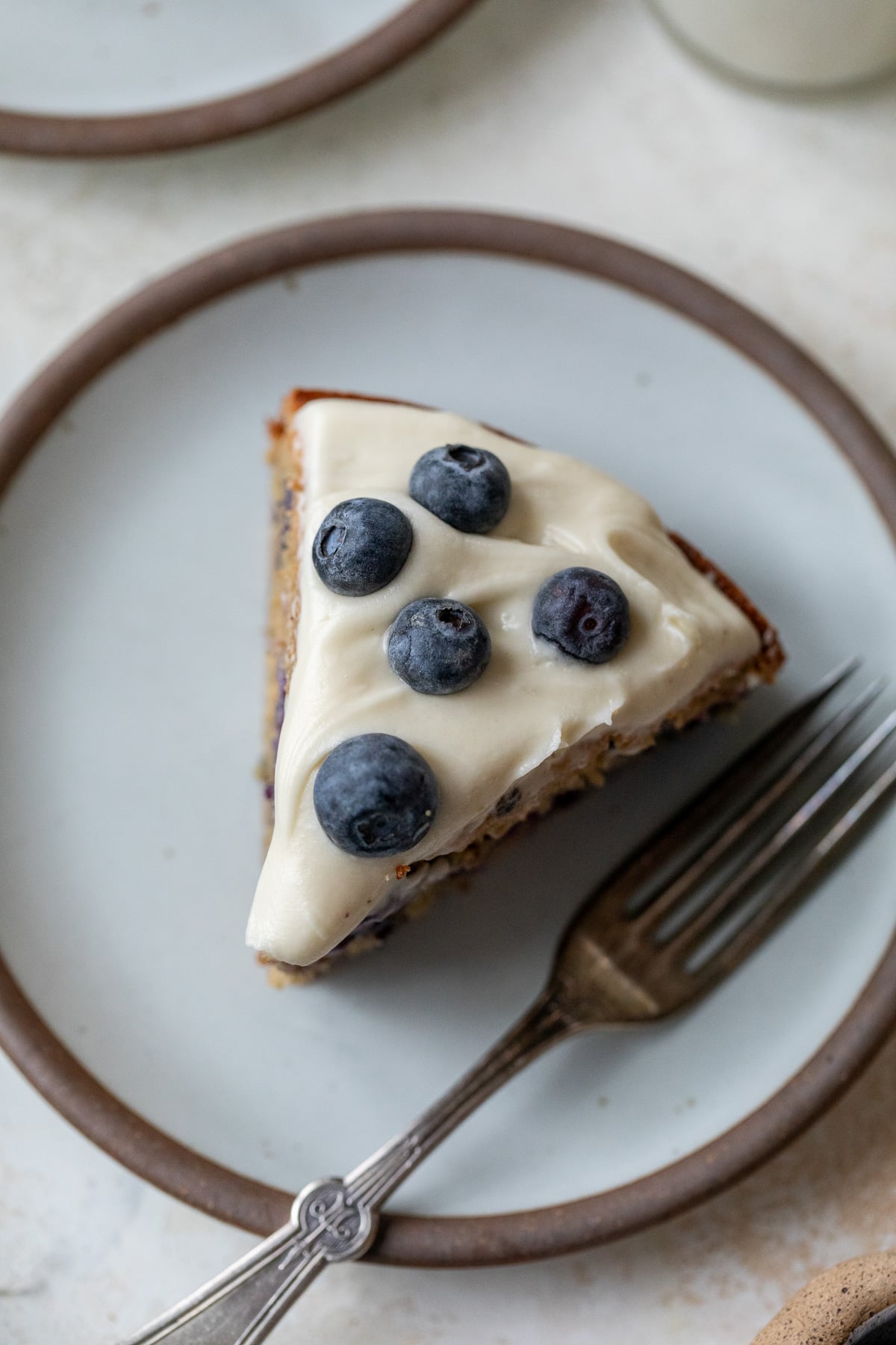 overview of a slice of blueberry cake on a plate with a fork