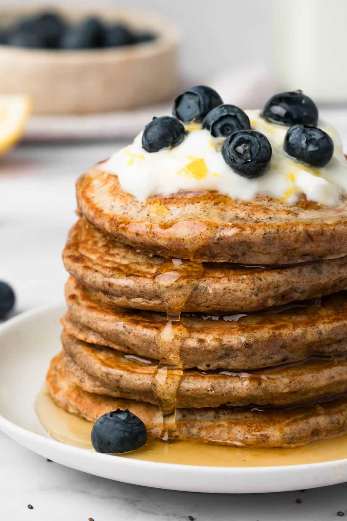 side view of chia seed pancakes topped with lemon yogurt and blueberries.