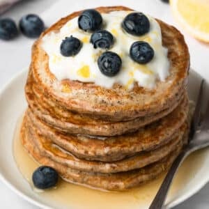 side view of chia seed pancakes topped with lemon yogurt and blueberries.