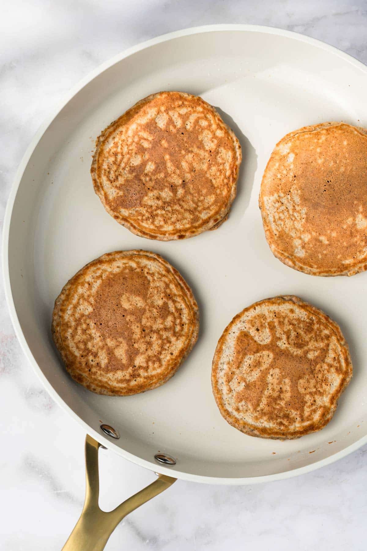 overhead view of 4 chia seed pancakes cooking in a skillet.