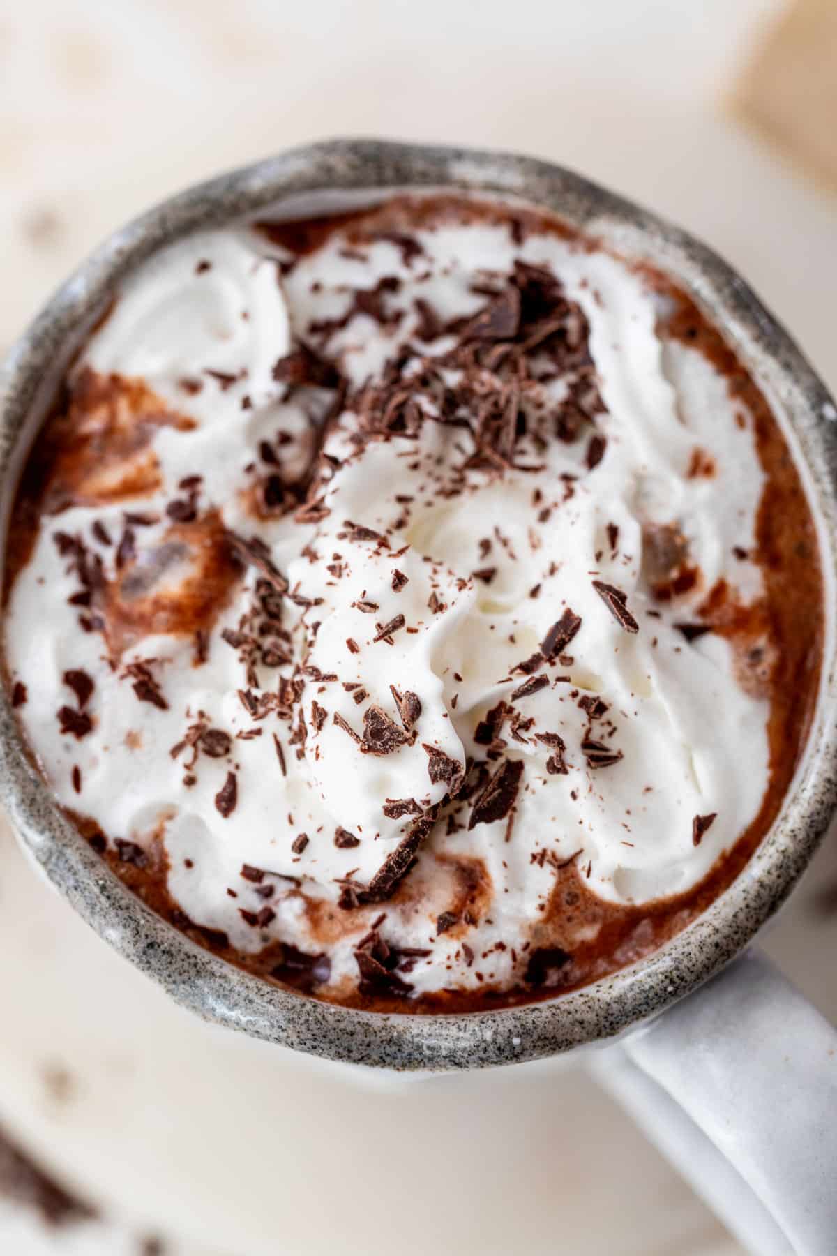 close up on a mug of boozy hot chocolate topped with whipped cream and chocolate shavings.