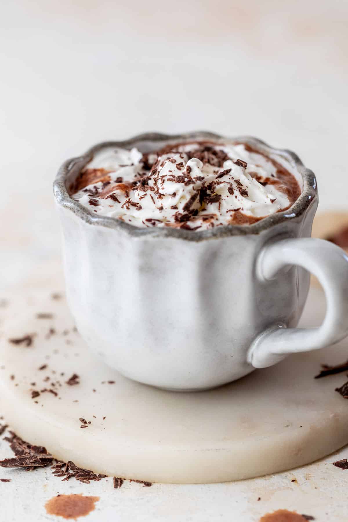 side view of a mug of boozy hot chocolate topped with whipped cream and chocolate shavings.