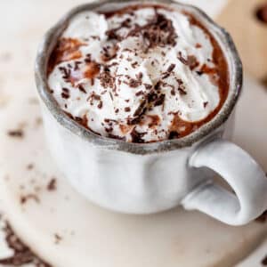 overhead view of a mug of boozy hot chocolate topped with whipped cream and chocolate shavings.