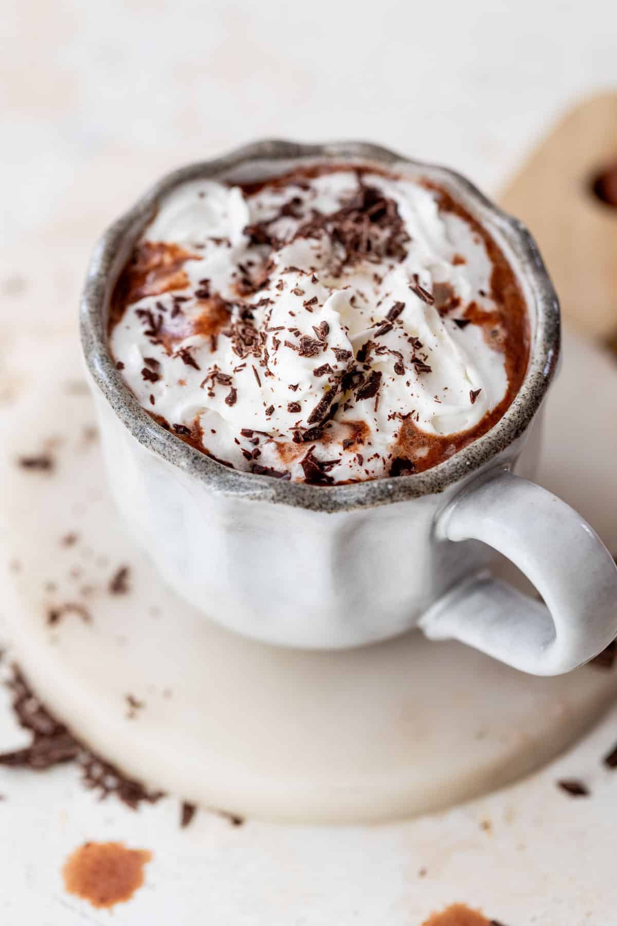 overhead view of a mug of boozy hot chocolate topped with whipped cream and chocolate shavings.