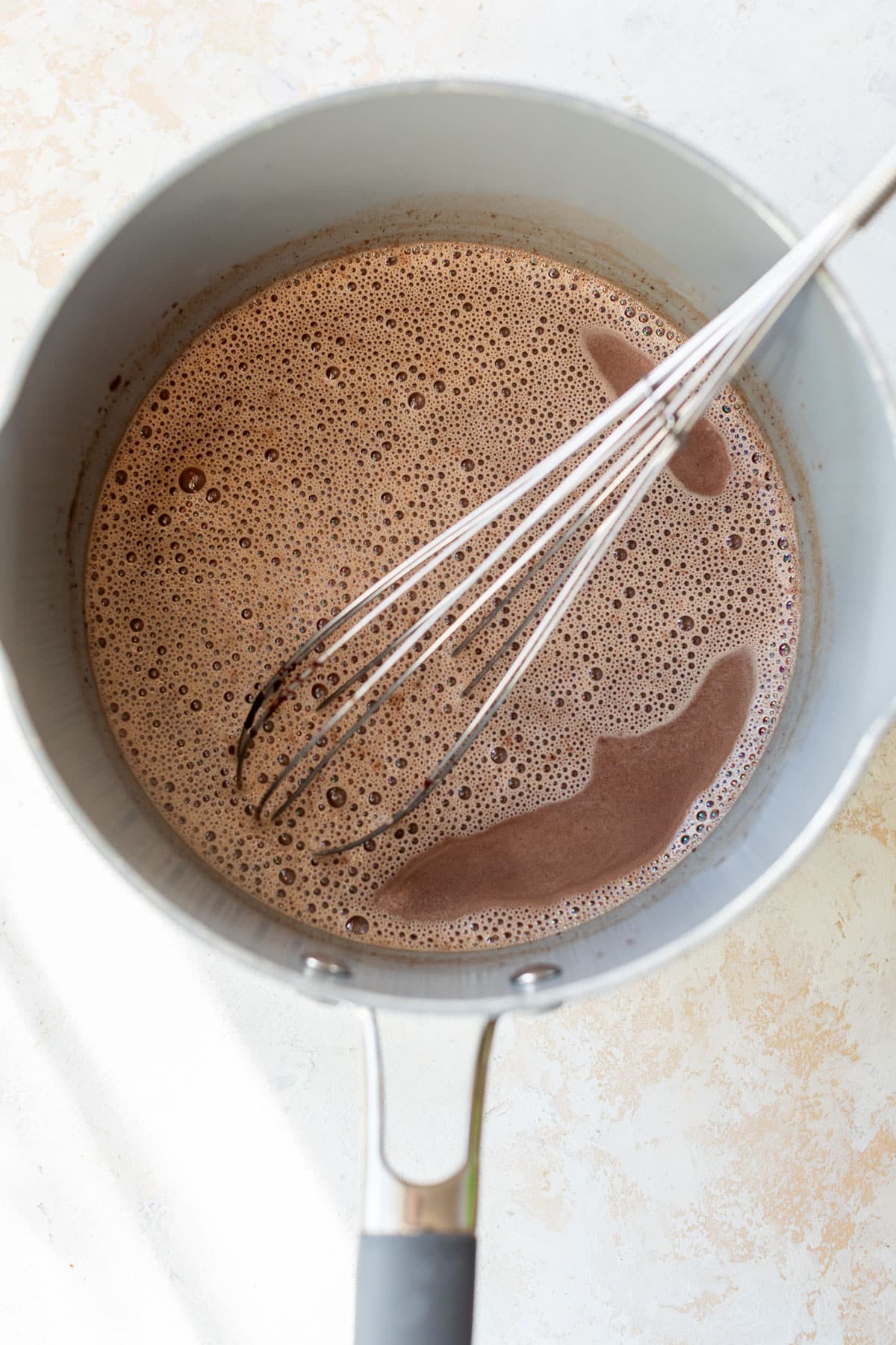 overhead view of a whisk in a pot of boozy hot chocolate.