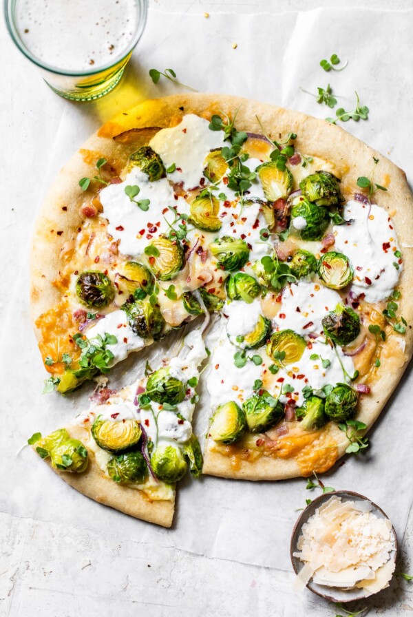 pizza on parchment paper beside a glass of beer