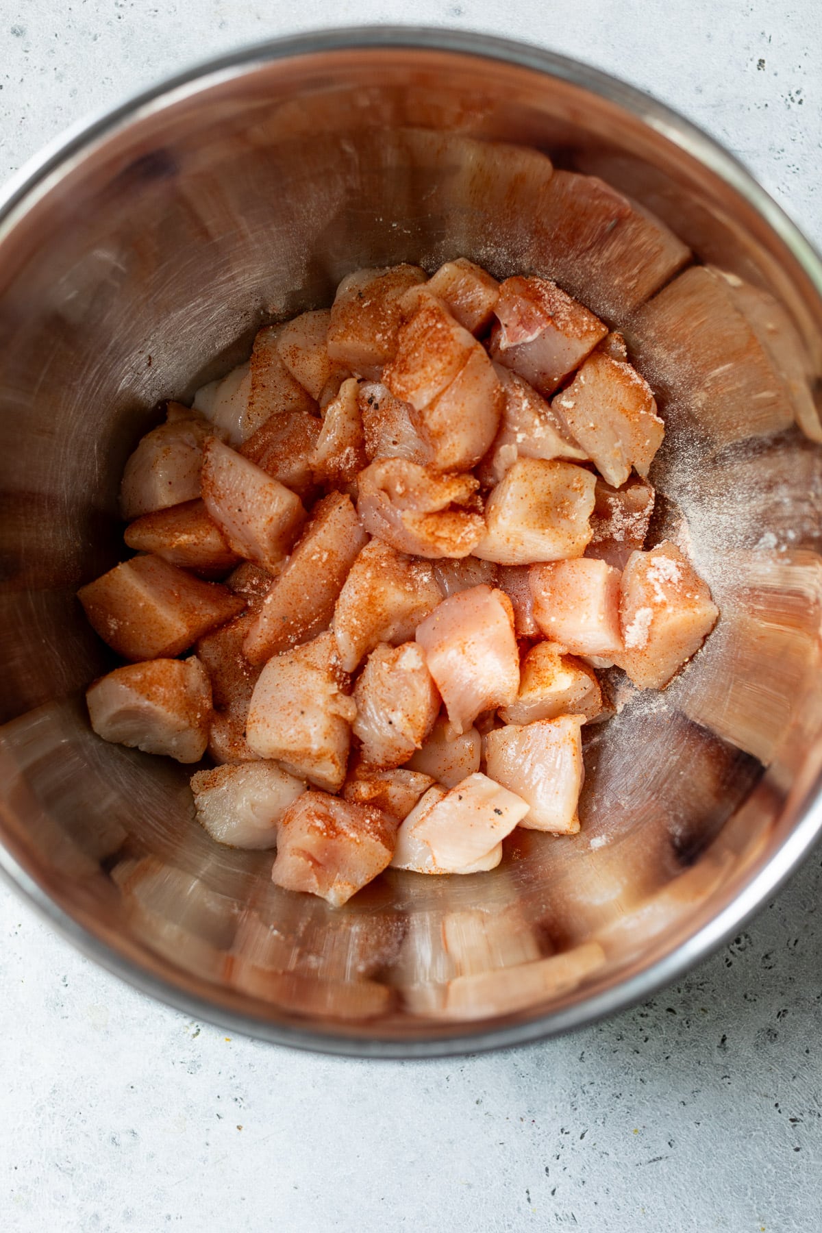 pieces of chicken breast in a large bowl with seasonings on top.