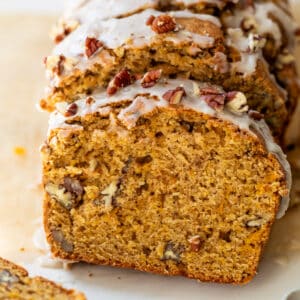 overhead view of a sliced loaf of butternut squash bread topped with a white glaze and pecans.