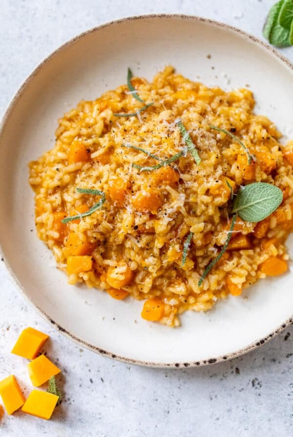 a plate of Butternut Squash Risotto topped with sage leaves and parmesan cheese.