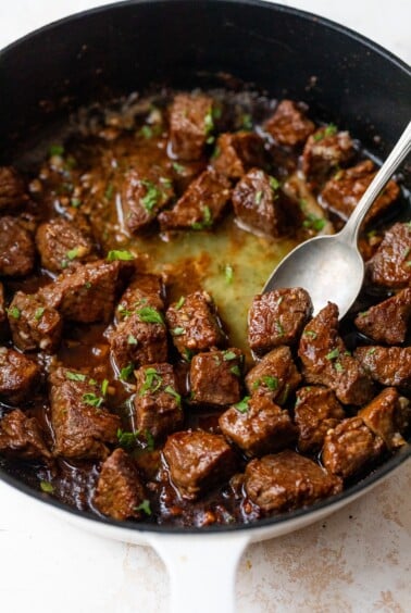 cajun steak bites in a skillet with a spoon