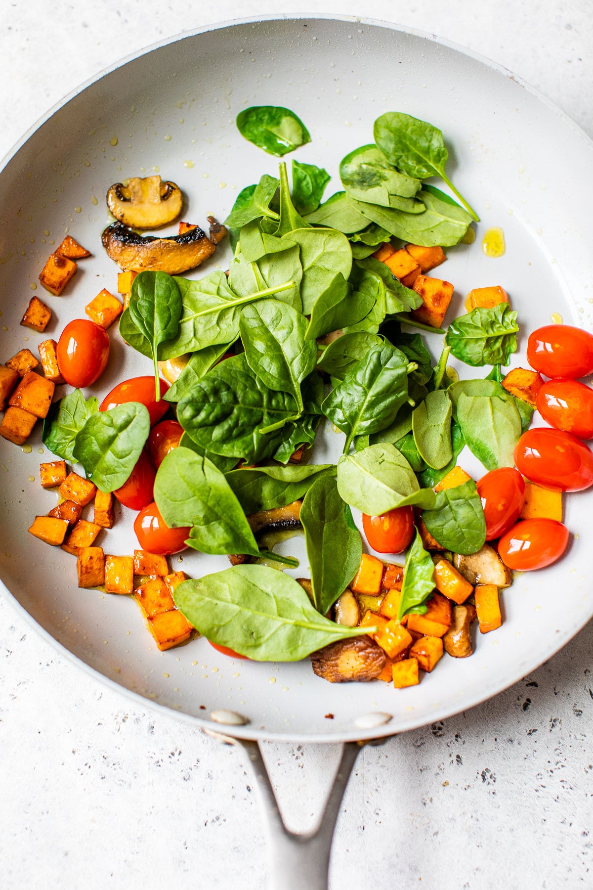 sweet potato, grape tomatoes and spinach in a skillet