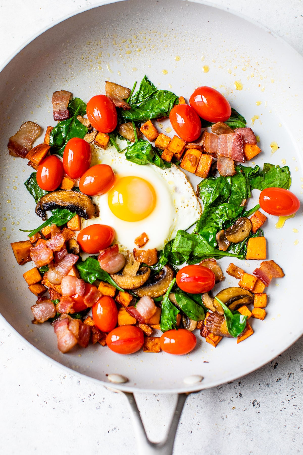 cooked vegetables in a skillet with a fried egg