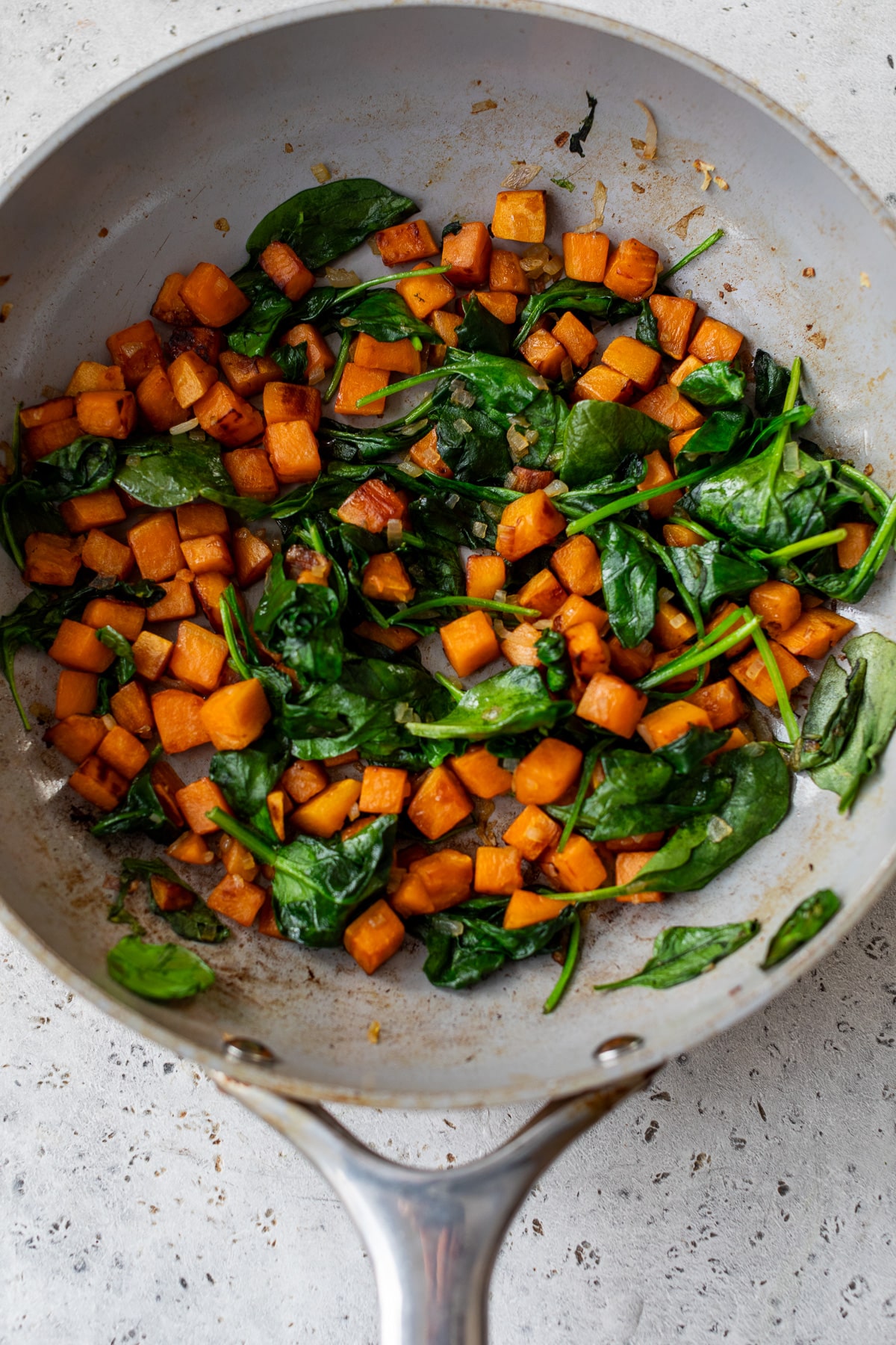 sweet potato and spinach cooking in a skillet