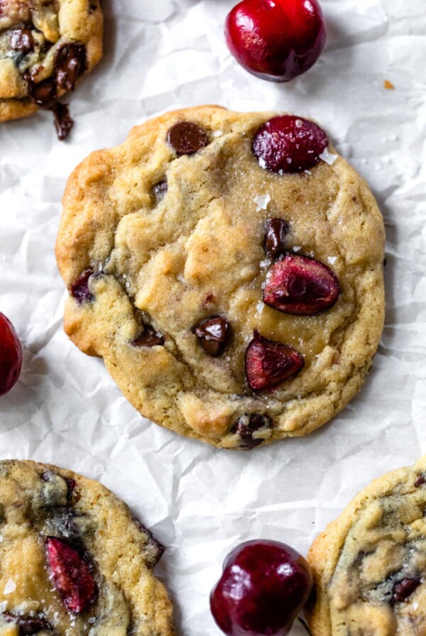 chocolate chip cookie with fresh cherries on a piece of parchment paper