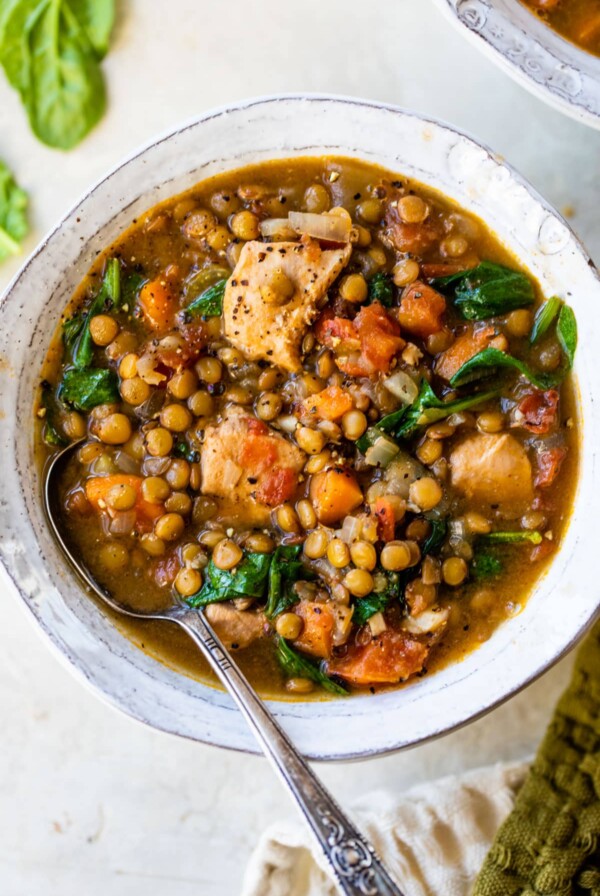 a bowl of soup with cooked diced chicken, green onions and vegetables