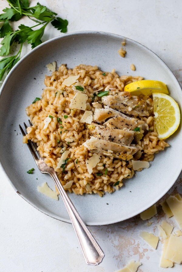 chicken risotto on a plate with lemon slices and a fork