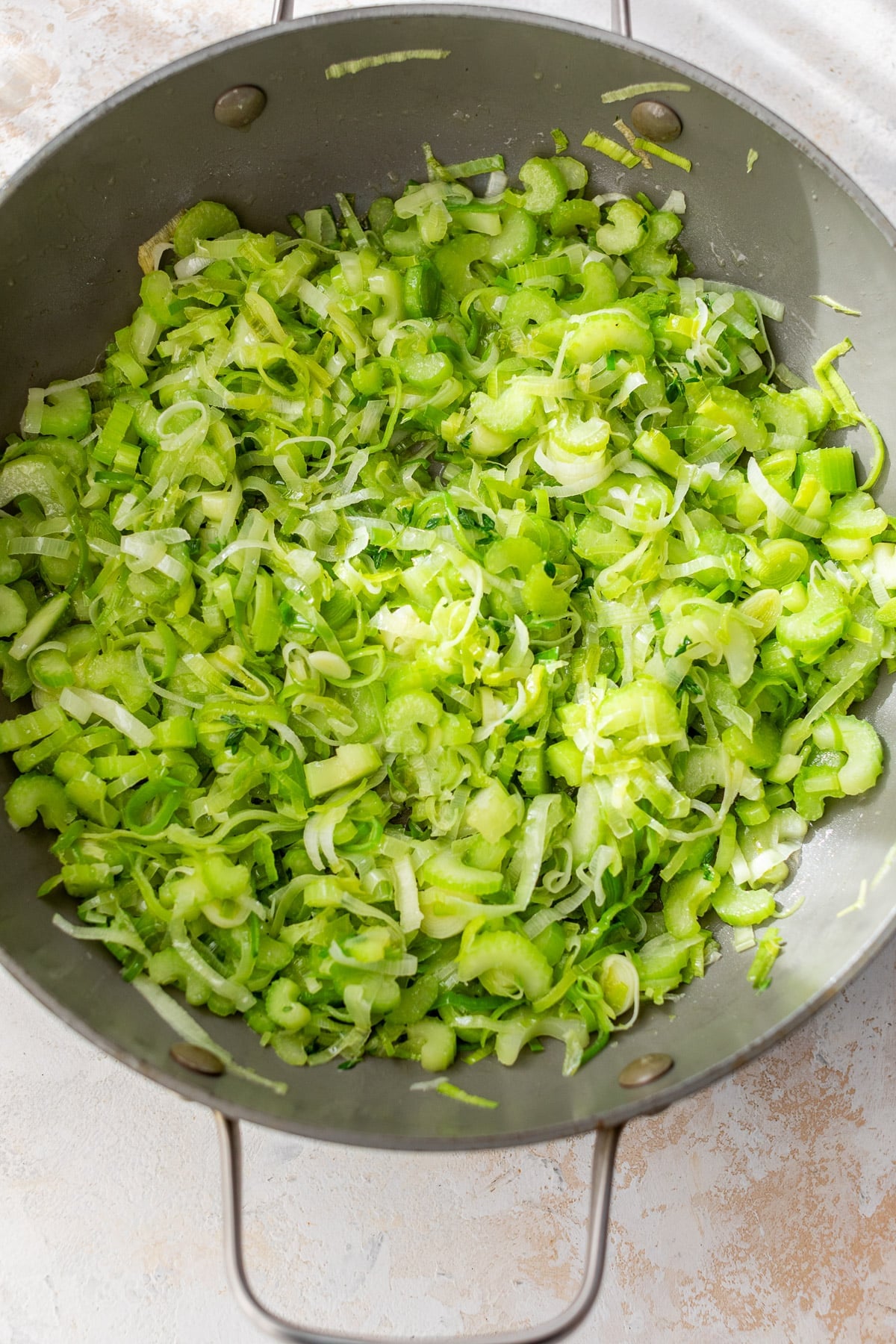 sauteeing sliced leeks and celery in a skillet.