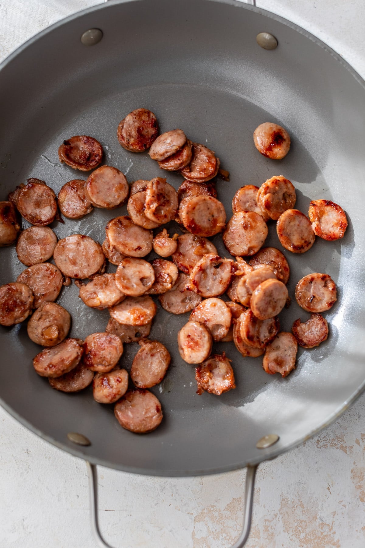 searing sliced chicken sausages in a skillet.