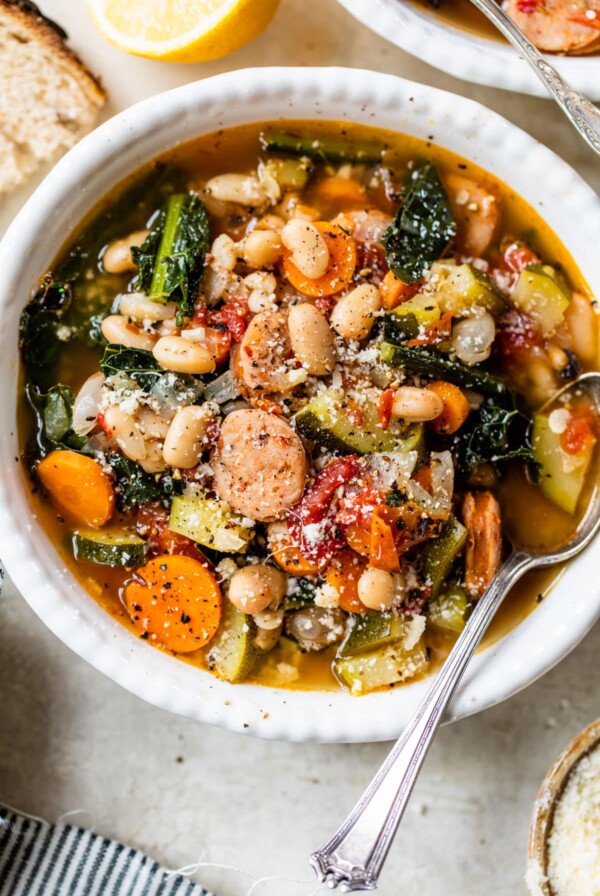 a bowl of soup with beans, sausage and kale