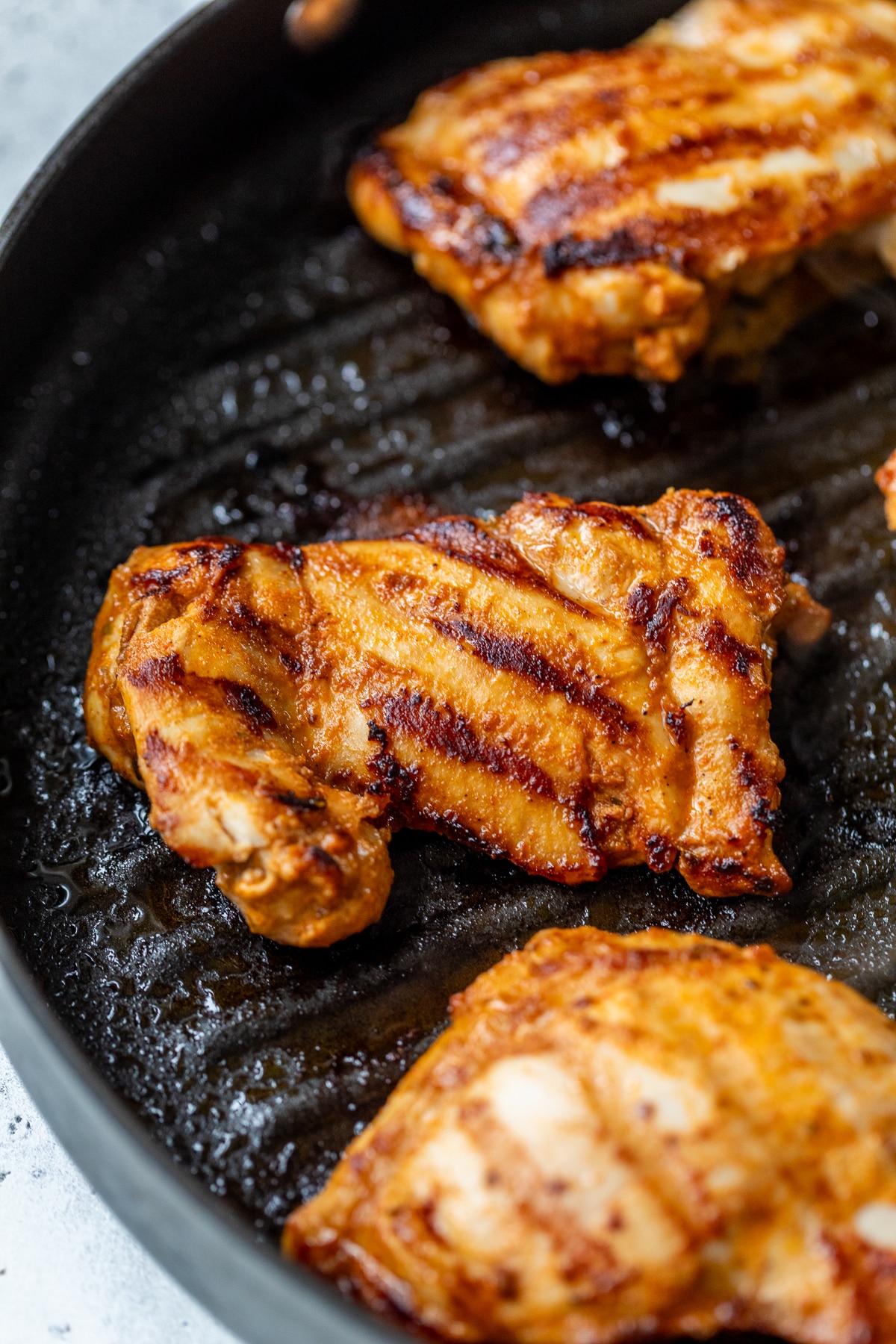 grilling chipotle chicken thighs in a black skillet.