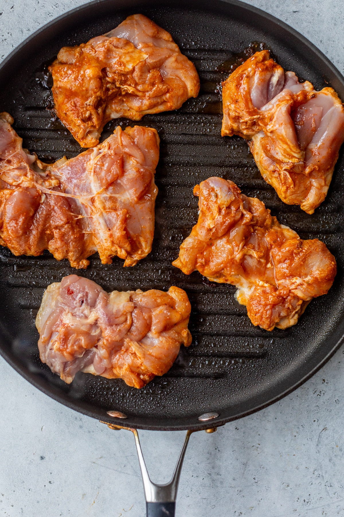 raw chipotle chicken thighs in a black grill pan.