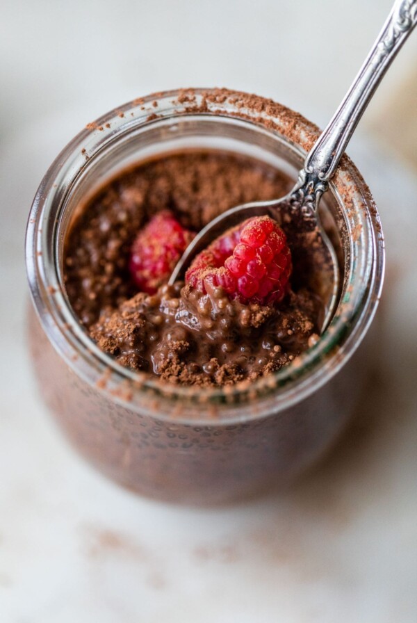 glass jar filled with chia pudding topped with raspberries