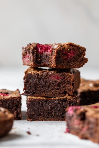 side view of three chocolate raspberry brownies stacked on top of each other