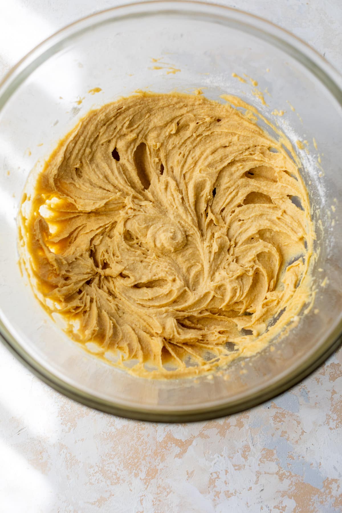 smooth, light brown cococnut flour cookie dough in a large glass bowls.